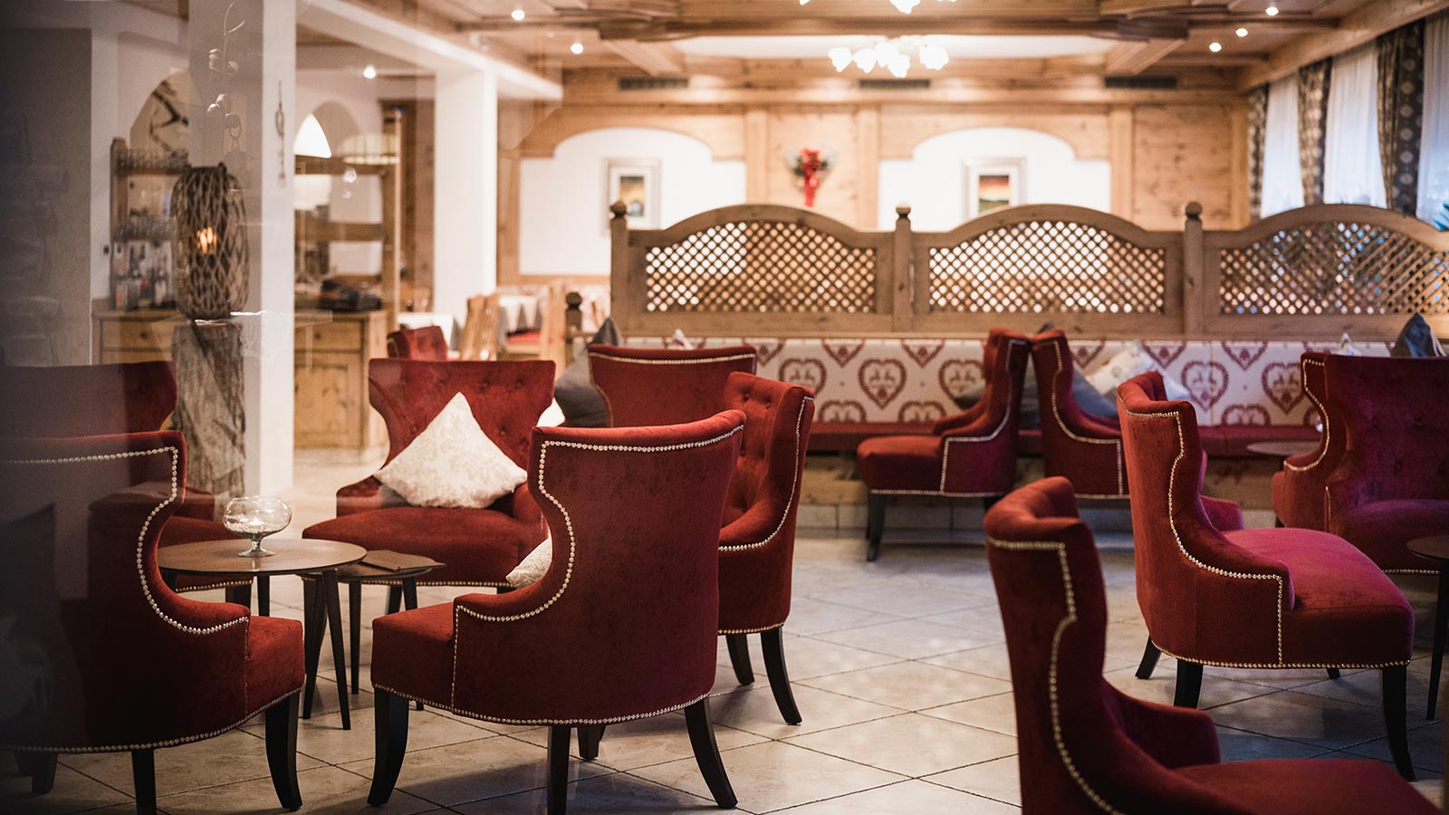 The bar of the Hotel Laguscei with red velvet armchairs and wooden walls