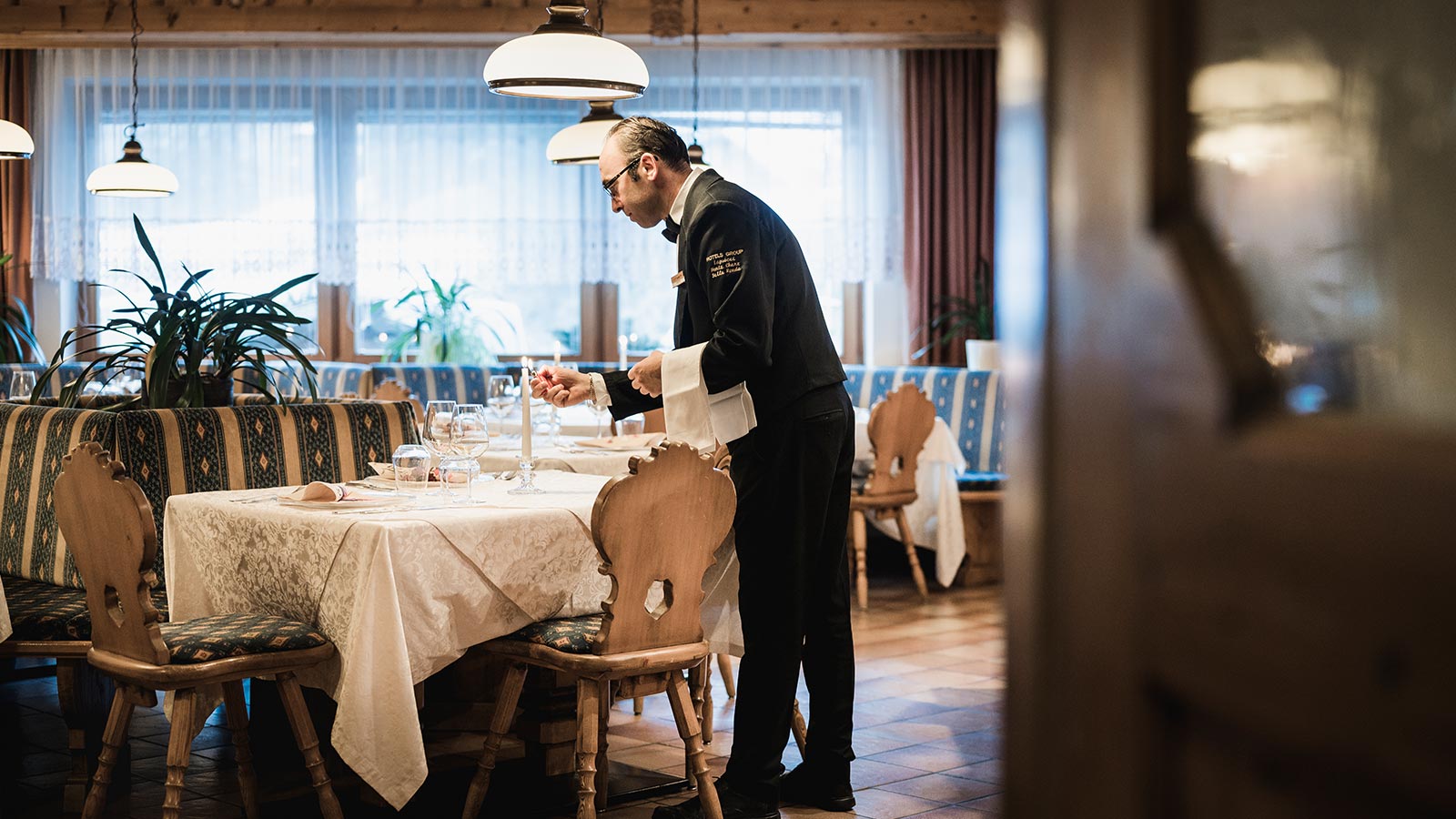 Ein Kellner entzündet eine Kerze im Esszimmer