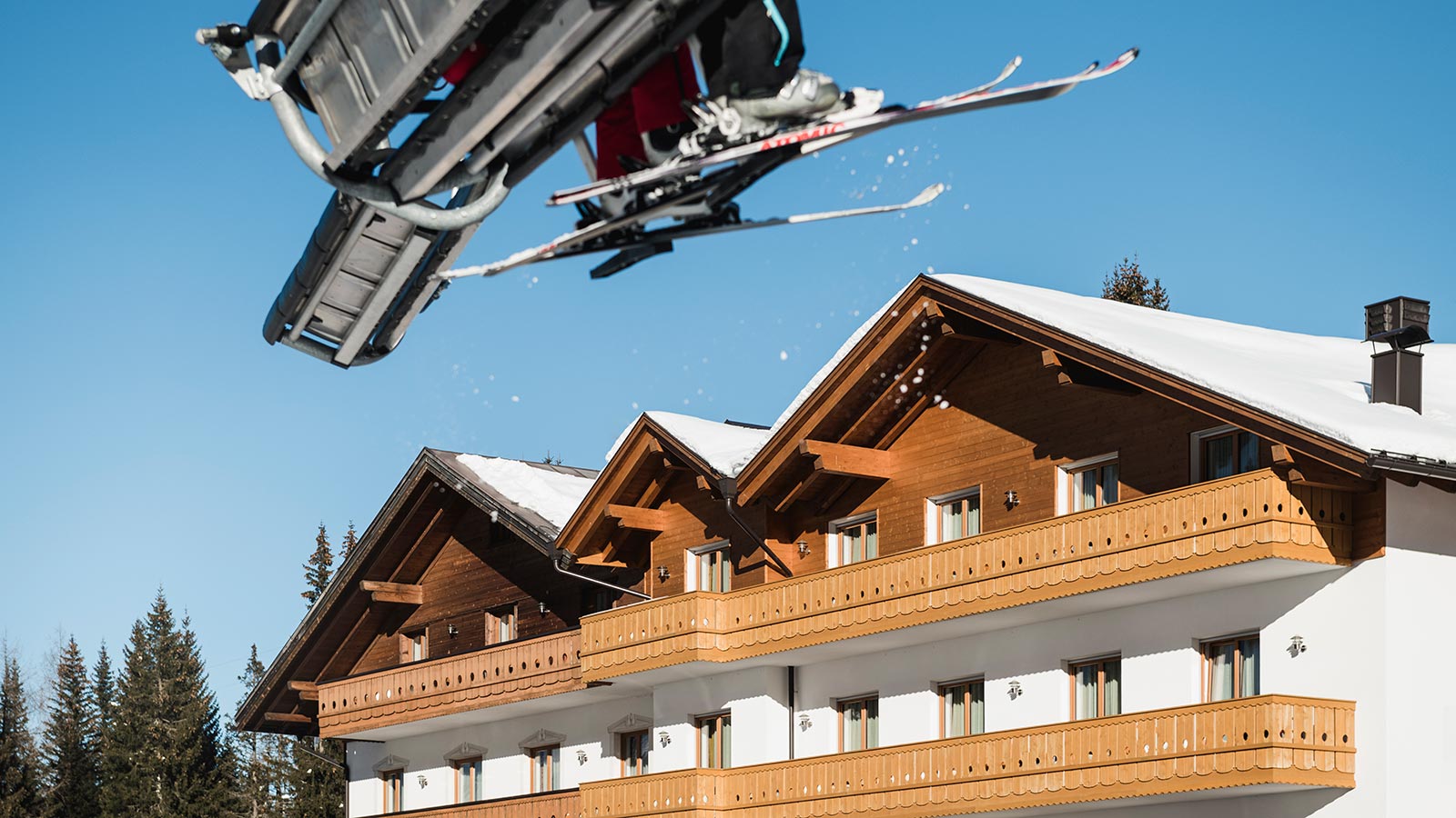 Detail einiger Skifahrer an der Seilbahn mit dem Hotel Laguscei in Arabba im Hintergrund
