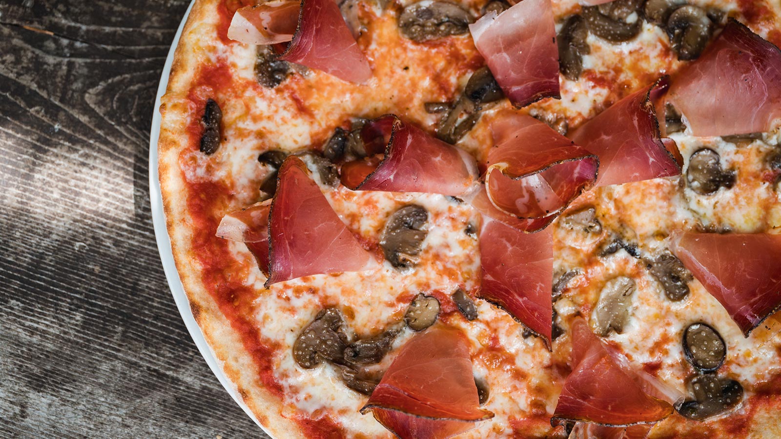 A tasty pizza with mushrooms and speck at the restaurant in Arabba